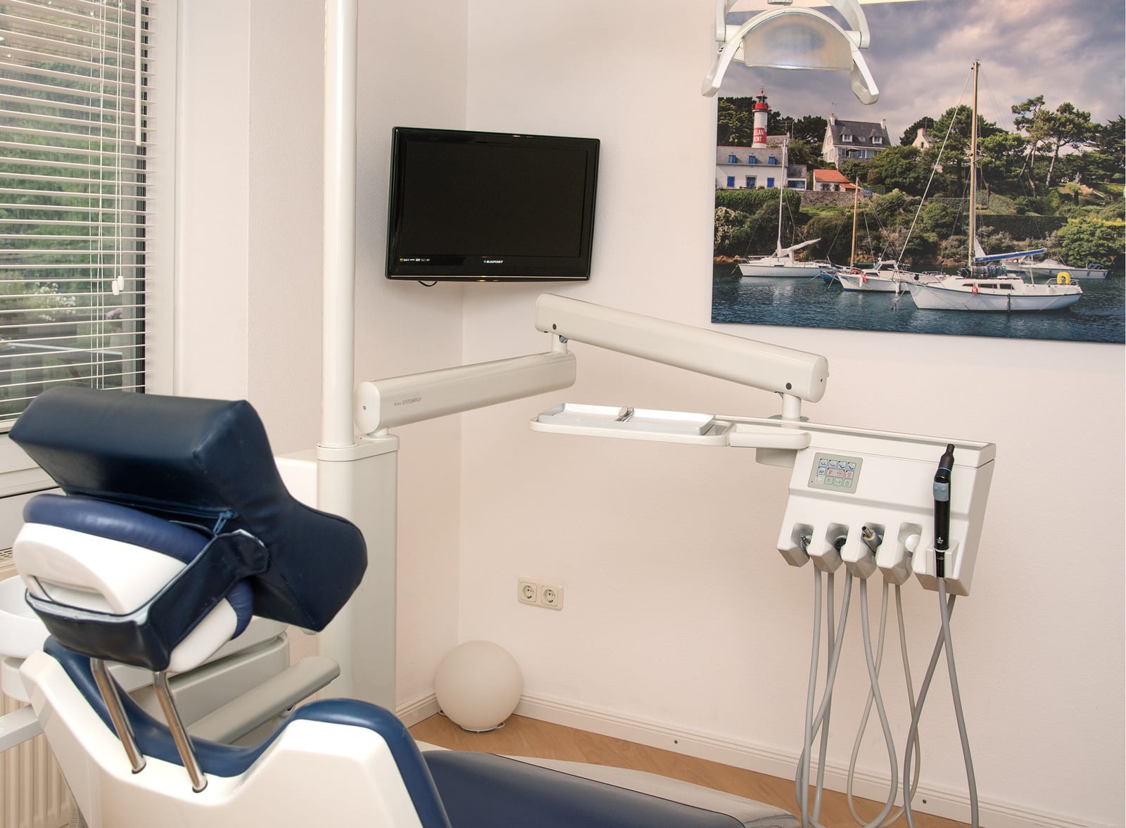 Behandlungszimmer mit Behandlungsstuhl und Bild eines Hafens